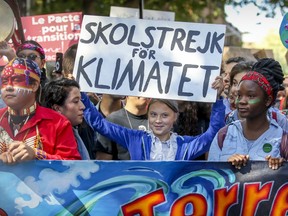 Greta Thunberg raises her climate strike sign while sharing the front row of climate march with Indigenous youths in Montreal on Friday.