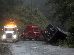 Search and rescue crews and RCMP help a tow-truck crew to remove a bus from the ditch of a logging road near Bamfield, B.C., on Saturday, September 14, 2019. (THE CANADIAN PRESS/Chad Hipolito)