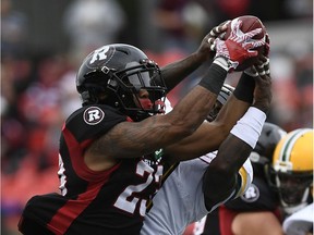 Ottawa Redblacks running back Mossis Madu Jr. reaches to control the ball against Edmonton Eskimos linebacker Larry Dean on Saturday.