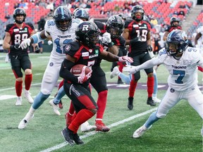 Stefan Logan of the Ottawa Redblacks makes the 1st down during a runback against Robert Woodson #7 and Nelkas Kwemo #12 of the Toronto Argonauts during a CFL game in the fourth quarter held at TD Place, on Saturday.