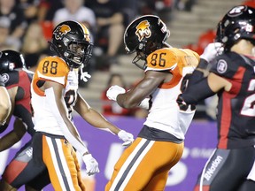 B.C. Lions’ Shaq Johnson (left) and Jevon Cottoy celebrate after a play while Redblacks’ Anthony Cioffi looks on during the second quarter on Saturday night in Ottawa.