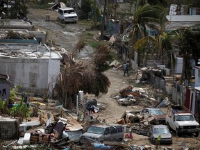 A man carrying a water container walks next to damaged houses after the area was hit by Hurricane Maria in Canovanas, Puerto Rico, September 26, 2017.