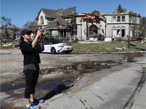 An unidentified woman takes a photo in front of the tornado-damaged home of Stars forward Tyler Seguin on Monday.