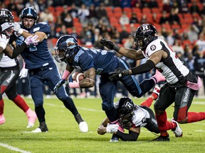 Argonauts running back James Wilder Jr. (right) is stopped by Redblacks defensive lineman 
Kene Onyeka and defensive back 
Kishawn McClain in Toronto last night.  
The Canadian Press