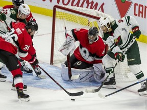 Ottawa Senators goaltender Craig Anderson holds his net against Minnesota Wild Ryan Hartman as Sens Colin White clears the puck during NHL action at the Canadian Tire Centre on Monday.