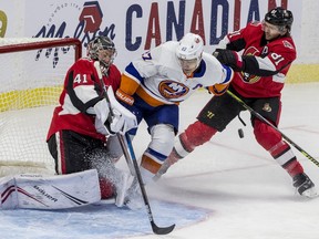 Senators defenceman Ron Hainsey tries to steer Islanders forward Anders Lee away from the crease of goalie Craig Anderson during Friday's game.