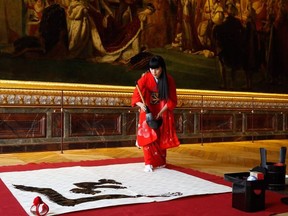 Japanese artist Yukako Matsui uses a traditional calligraphy brush and ink to write the name of Japan's new era of "Reiwa" ("beautiful harmony" in English) on paper in the hall of coronation of The Chateau de Versailles in Versailles, near Paris on Monday in honour of the forthcoming coronation of Japan's new Emperor.