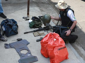A policeman remains next to guns and money bags seized to criminals who raided the cargo terminal of the Viracopos International Airport, in Campinas, Brazil, on October 17, 2019. (LEANDRO FERREIRA/AFP via Getty Images)