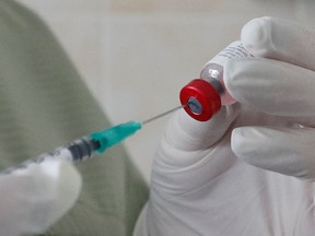 A nurse fills a syringe with a vaccine