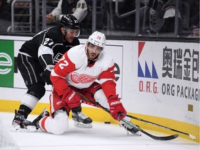 Andreas Athanasiou of the Detroit Red Wings is pushed past the puck by Alec Martinez of the Los Angeles Kings during the first period at Staples Center on November 14, 2019 in Los Angeles, California.