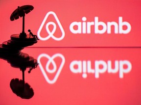 In this file photo illustration, a toy umbrella and a figurine on coins are seen next to the logo of rental website Airbnb.