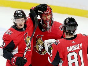 Thomas Chabot (L) and Ron Hainsey congratulate Anders Nilsson on the win at the end of the game as the Ottawa Senators take on the Carolina Hurricanes in NHL action at the Canadian Tire Centre in Ottawa.