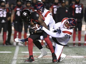 Ottawa Redblacks quarterback Dominique Davis gets sacked by Montreal Alouettes defensive back Patrick Levels and linebacker Boseko Lokombo (20) during first-half CFL football action at TD Place stadium on Friday, Nov. 1, 2019.
