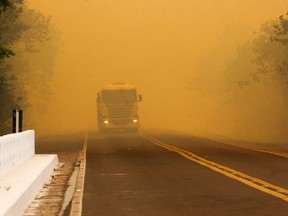 Handout picture released by Mato Grosso do Sul State Government shows a truck being driven on a road covered by smoke from a forest fire at the Pantanal ecoregion of Brazil, municipality of Corumba, Mato Grosso do Sul state, on Oct. 30, 2019.
