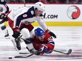 Canadiens forward Jonathan Drouin passes the puck as he falls beneath the defensive pressure of the Blue Jackets' Zach Werenski (8) during the third period of Tuesday's game in Montreal.