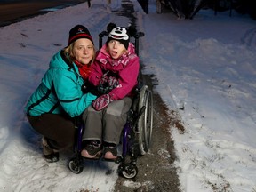 Christine Dalgliesh and her daughter, Abby, pose for a photo outside their home in Ottawa on Wednesday. They are having a lot of trouble getting through snow on unplowed sidewalks, and this week Christine even shovelled a path for the chair all the way to Smyth Road.