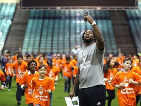 Saskatchewan Roughriders running back Jerome Messam  uses his phone to capture students running a lap during a Jumpstart event at the RBC Convention Centre that is part of CFL Week in Winnipeg on Thurs., March 22, 2018.