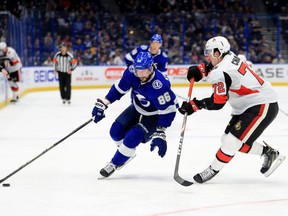 Nikita Kucherov #86 of the Tampa Bay Lightning and Thomas Chabot #72 of the Ottawa Senators fight for the puck during a game  at Amalie Arena on December 17, 2019 in Tampa, Florida.