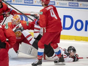 Canada's Alexis Lafreniere is upended by Russia's Yegor Zamula, centre, in front of Russia goaltender Amir Miftakhov, left, during first period action at the World Junior Hockey Championship, Saturday, Dec. 28, 2019 in Ostrava, Czech Republic. (THE CANADIAN PRESS/Ryan Remiorz)