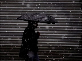 A person walks with an umbrella in the snow.