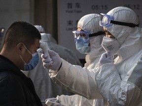 A Chinese health worker checks the temperature of a woman entering a subway station during the Chinese New Year and Spring Festival on January 25, 2020 in Beijing, China.