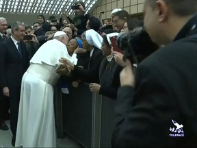 Pope Francis kisses a nun on the cheek after making a joke to her saying "You bite! I will give you a kiss but you stay calm. Don't bite!" as he arrives for the general audience at the Vatican, in this still image taken from a video, Jan. 8, 2020. (Vatican Media/Handout via REUTERS)