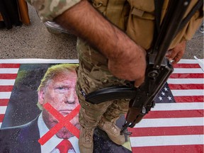 A member of Iraq's Hashed al-Shaabi paramilitary network stands on a U.S. flag during a symbolic funeral procession for the network's deputy Abu Mahdi al-Muhandis in the southern city of Basra, on Jan. 4, 2020.