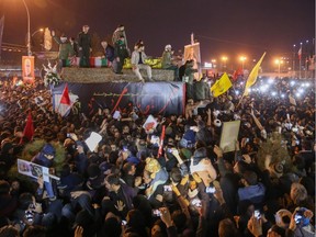 Iranians gather around a vehicle carrying the caskets of slain military commander Qasem Soleimani and others during a funeral procession after the bodies arrived in the northeastern city of Qom on Monday following a ceremony in the capital Tehran.