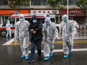 This photo taken on January 26, 2020 shows medical staff members wearing protective clothing to help stop the spread of a deadly virus which began in the city, accompanying a patient (2nd from the left) as they walk into a hospital in Wuhan in China's central Hubei province.