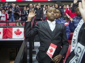 Ahmed Mohammed, 11, holds his hand up while taking the oath of citizenship during Saturday's ceremony at Canadian Tire Centre before the NHL game between the Senators and visiting Calgary Flames.