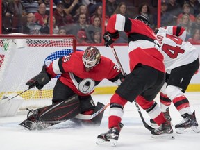 Ottawa Senators goalie Marcus Hogberg makes a save in front of New Jersey Devils forward Miles Woods.