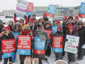 Elementary teachers pose for a group photo in the freezing rain outside Molly Brant Elementary School in Kingston, Ont. on Thursday, Feb. 6, 2020, during the province wide Elementary Teachers' Federation of Ontario labour strike.