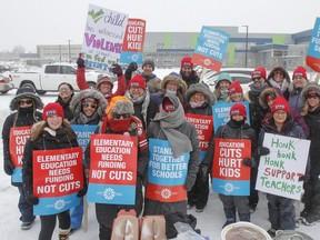 Elementary teachers pose for a group photo in the freezing rain outside Molly Brant Elementary School in Kingston, Ont. on Thursday, Feb. 6, 2020 during the provincewide Elementary Teachers' Federation of Ontario labour strike.