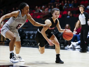 Kali Pocrnic of Carleton drives past defender Tyra Blizzard in the women's Capital Hoops Classic basketball game between the University of Ottawa and Carleton University.