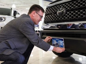 MPP Bill Walker holds up a new Ontario commercial vehicle licence plate on the front bumper of a truck. All licence plates issued in Ontario will be modelled off this new plate design starting Feb. 1, 2020, according to a news release from Walker's office.