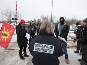An enforcement officer reads an injunction to Tyendinaga Mohawk protesters at a rail blockade, near Belleville, on Feb. 11, 2020. (The Canadian Press)