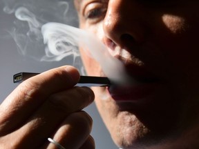 In this file illustration taken on October 2, 2018, a man exhales smoke from an electronic cigarette in Washington, DC.