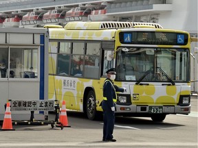 A bus carrying passengers who disembarked from the Diamond Princess cruise ship (back), in quarantine due to fears of the new COVID-19 coronavirus, leaves the Daikoku Pier Cruise Terminal in Yokohama on Feb. 20, 2020.