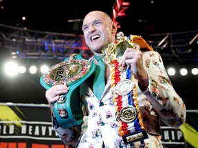 Tyson Fury poses with his belts during a press conference after the fight.
