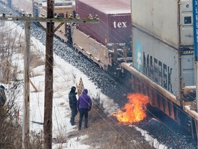 A fire burns next to a passing Canadian National Railway (CN Rail) train beside an encampment of the Tyendinaga Mohawk Territory, set up in support of the Wet'suwet'en Nation.