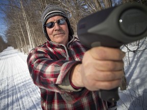 Almonte resident Bruce Matheson uses a radar gun to clock snowmobile riders on the Ottawa Valley Rail Trail where it passes through town.