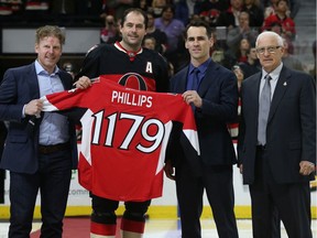 Chris Phillips receives a jersey with the number 1179 representing the number of games he had played with the Senators from Daniel Alfredsson, left, Wade Redden and Bryan Murray during a pre-game ceremony on Feb. 5, 2015.