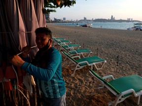 A man collects his umbrellas on an almost empty beach which usually crowed with tourists following the coronavirus disease (COVID-19) outbreak in Pattaya, Thailand March 27, 2020. (REUTERS/Soe Zeya Tun)