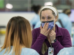 A nurse demonstrates how to wear a face mask properly at the Brewer Arena assessment centre.