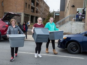 Mom Joan Desmarais, left, and sister Jenna Desmarais, middle, help Emily Desmarais move her belongings out of a residence building at Carleton University.