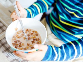 Closeup of child's hands eating cereal for breakfast.