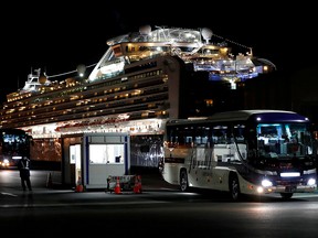 In this Feb, 21, 2020, file photo, a bus transporting Hong Kong passengers from the coronavirus-hit cruise ship Diamond Princess leaves the Daikoku Pier Cruise Terminal in Yokohama, south of Tokyo, Japan.