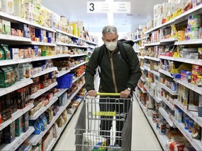 Doug Hassebroek shops with a protective mask during the outbreak of COVID-19 in Brooklyn, N.Y., Wednesday, March 25, 2020.