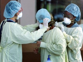 Health care workers help a visitor going to the intensive care unit put on a gown and mask. (File photo)