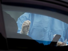 A nurse holds out a nasal swab for a patient at a coronavirus testing site.